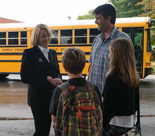 Image of Delegate Murphy talking to parents and a student in front of a school bus